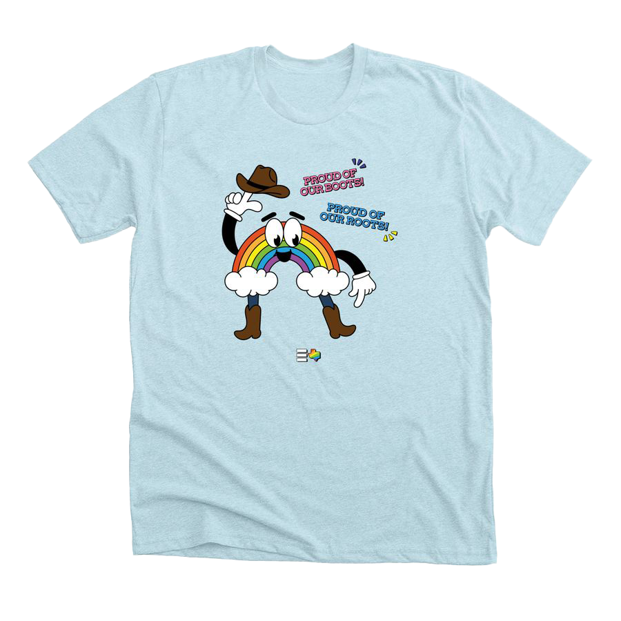 Light blue t-shirt with a smiling rainbow cartoon character wearing cowboy boots and holding a cowboy hat. Next to the character, text says "Proud of our boots, proud of our roots"