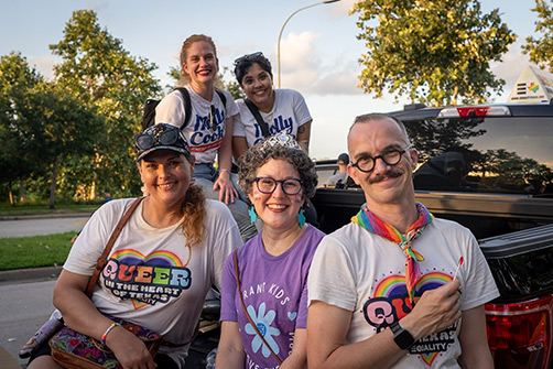 A small group of Houston Pride attendees sitting in the bed of a truck and smiling.