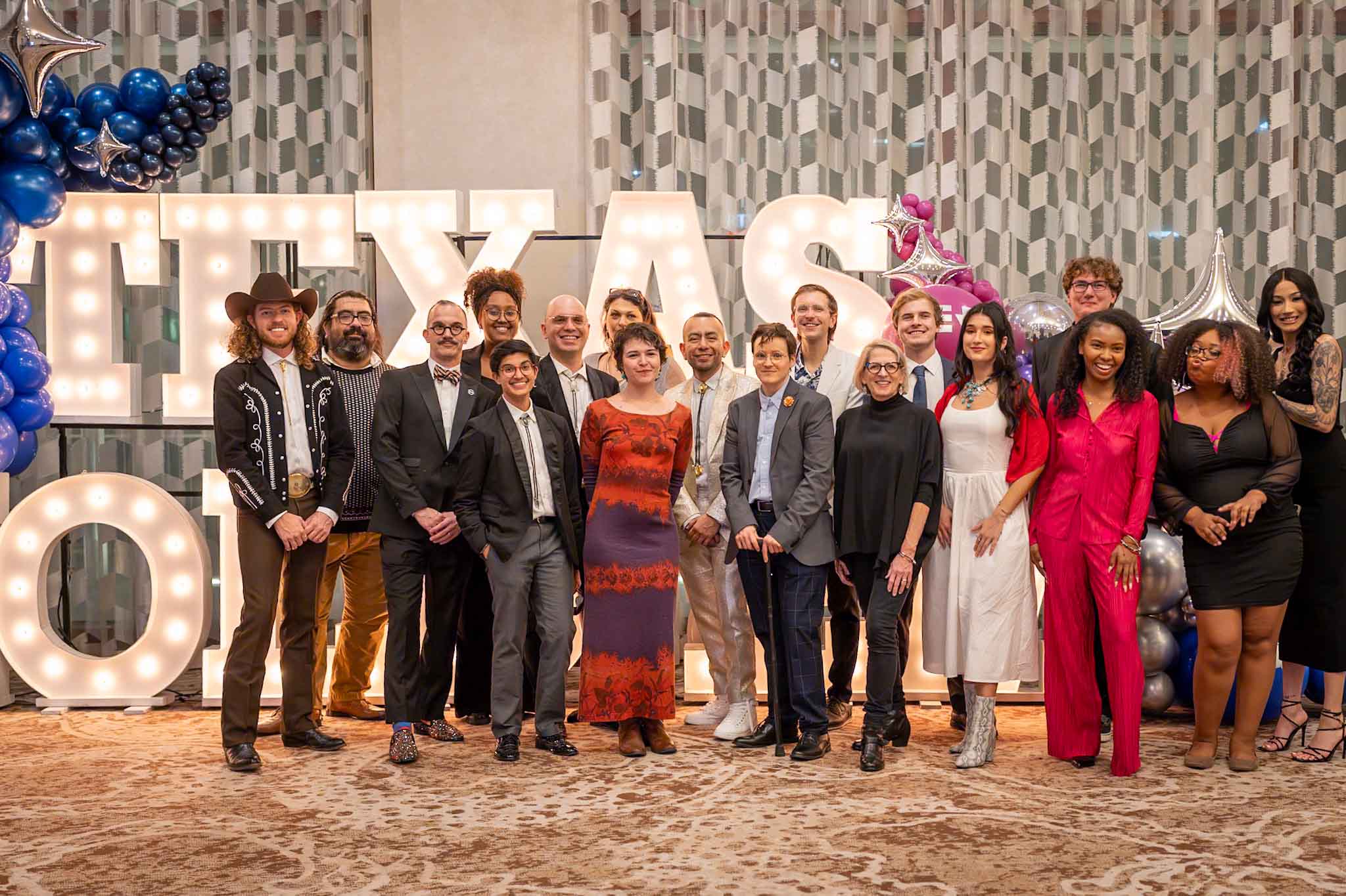 The Equality Texas Staff standing in front of large letters that read "Texas Hold 'Em" and smiling at the camera.